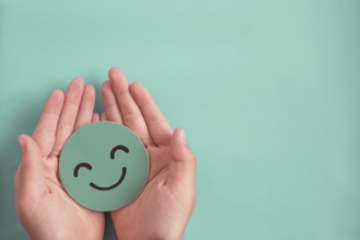 green smiley face image in palm of hands
